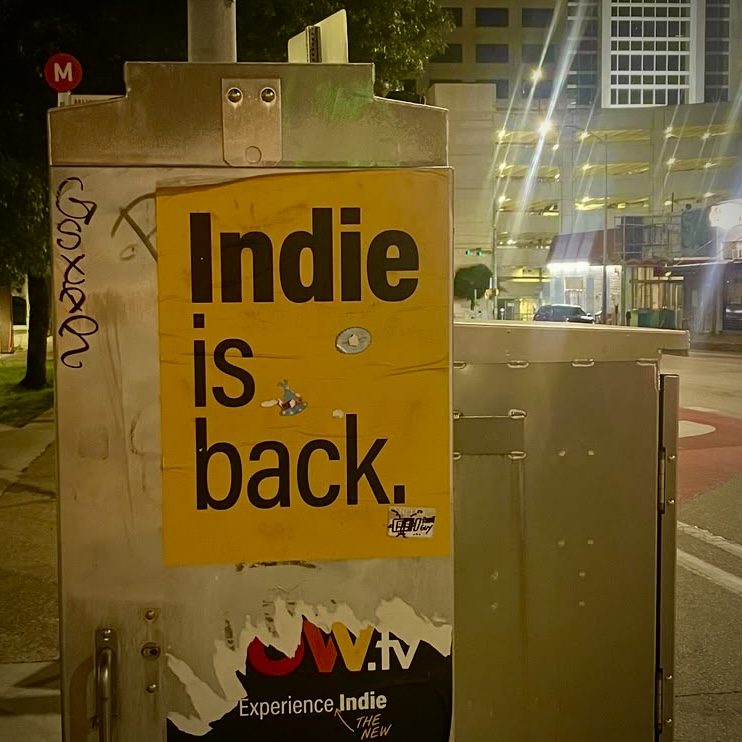 Playlist cover: a yellow street poster reading “Indie is back.” on a city utility box at night